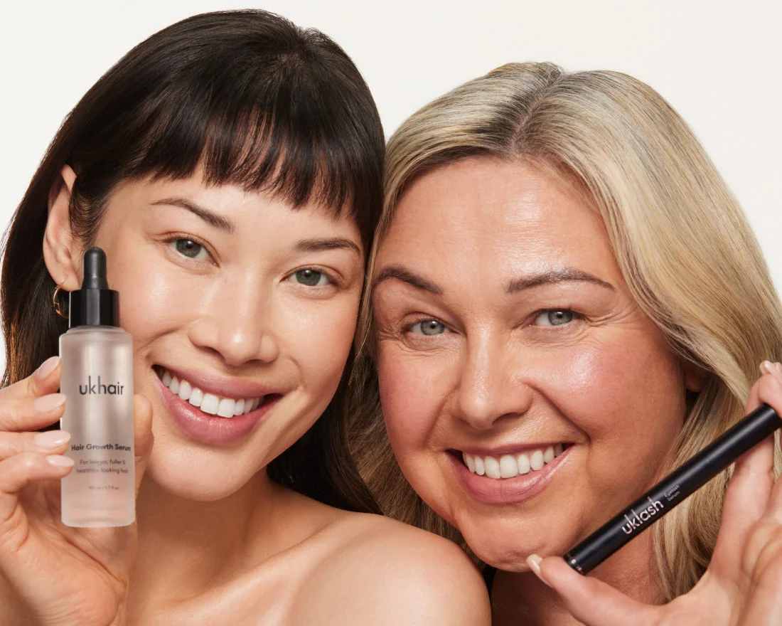 Two women of different ages smiling and holding UKHAIR Hair Growth Serum and UKLASH mascara.